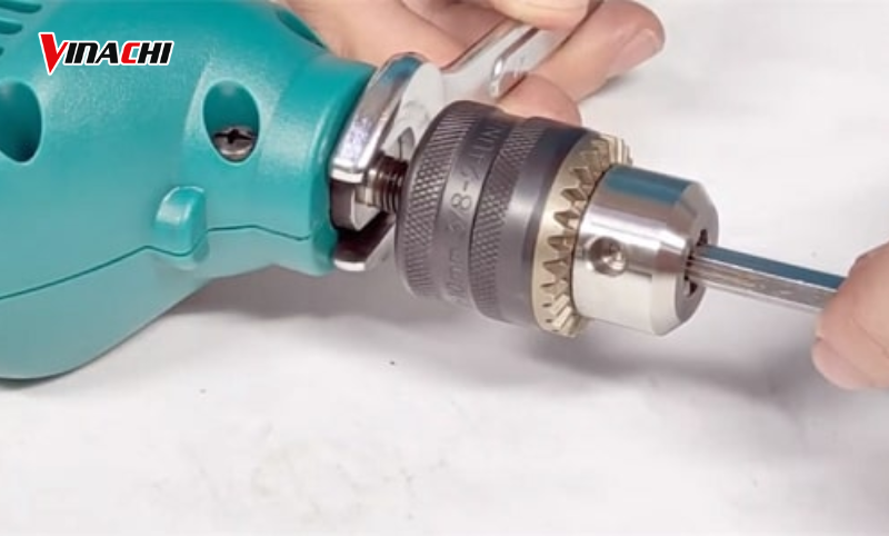 Dùng cờ lê giữ chặt phần trục máy khoan