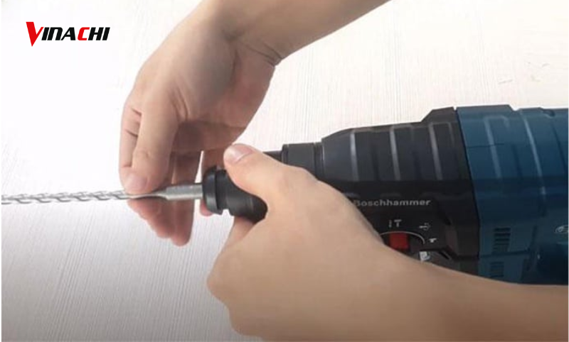 Một tay kéo phần đầu kẹp, một tay giữ chắc mũi khoan