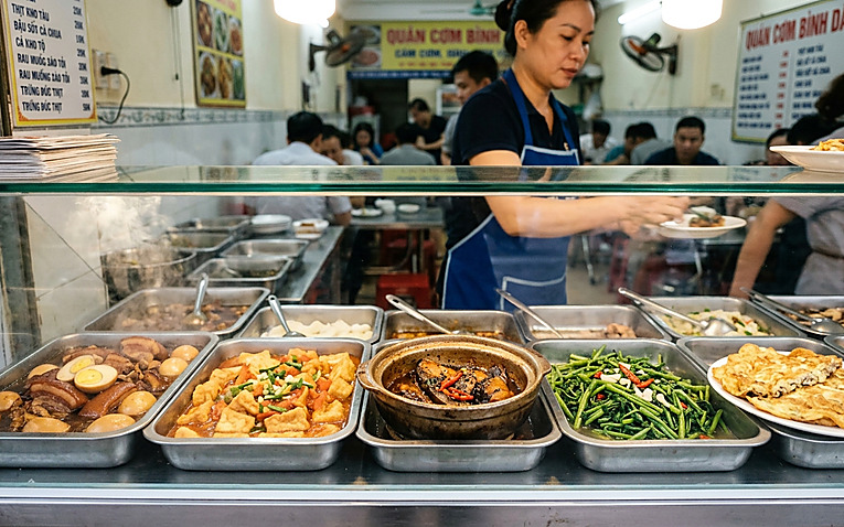 Tủ kính trưng bày các khay thức ăn nóng hổi, đa dạng món