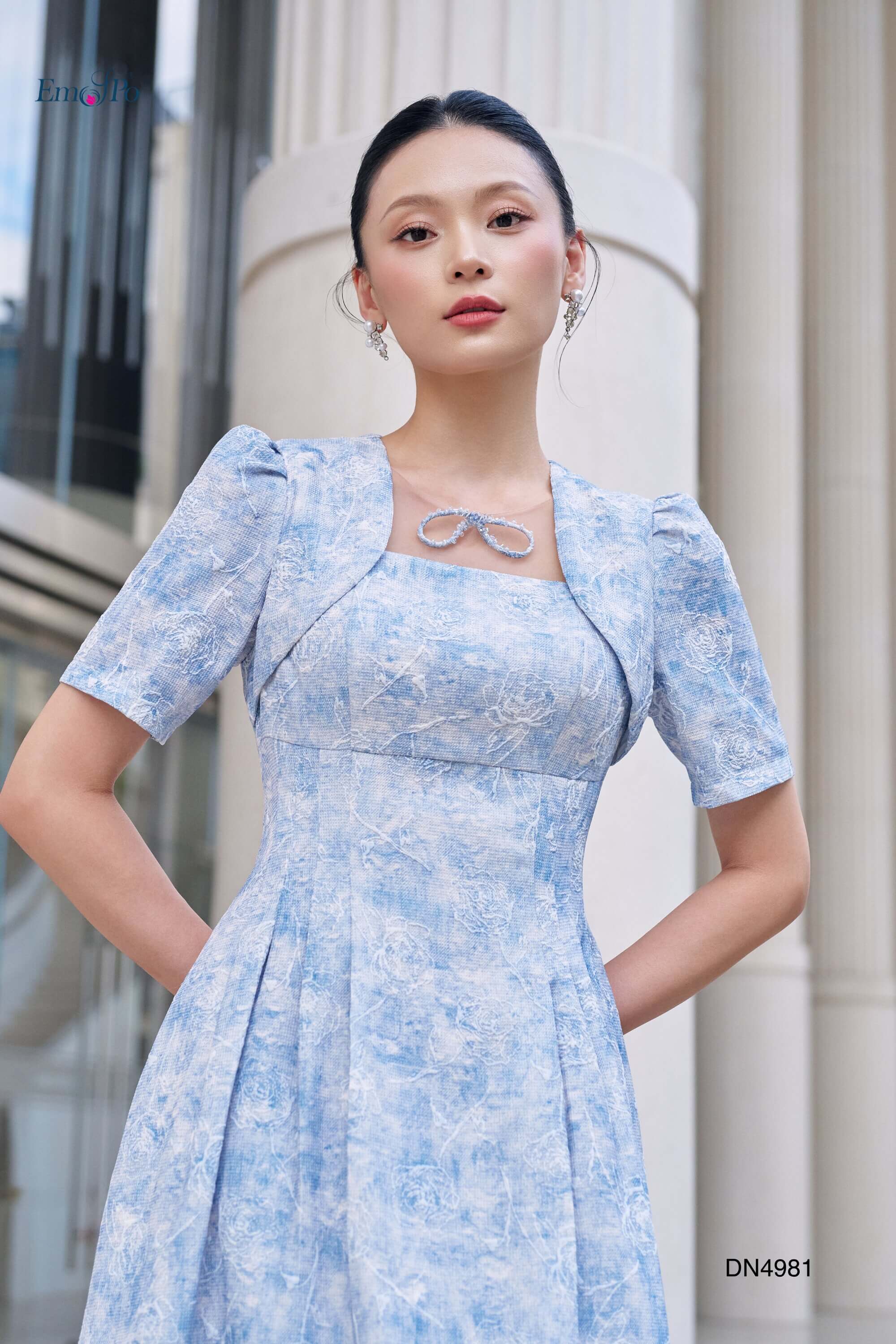 Đầm xòe cổ vuông giả choàng, phối lưới đính nơ cườm, xếp ly 2 bên hông