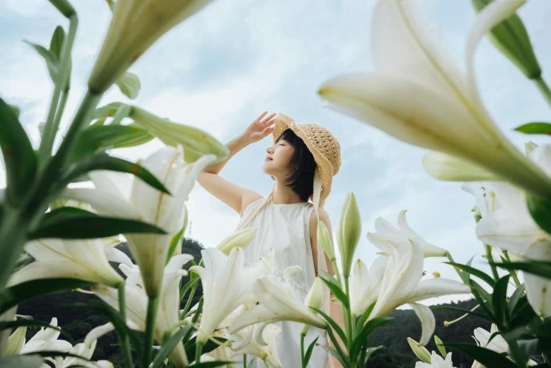 Đứng giữa đồng hoa, tay che nắng