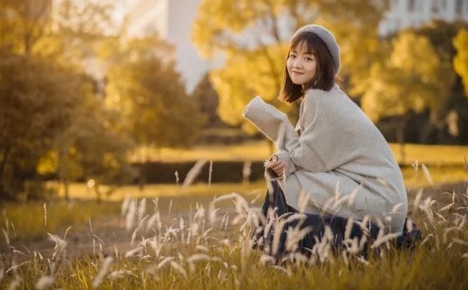 Ngồi giữa đồng cỏ úa và nhìn vào camera