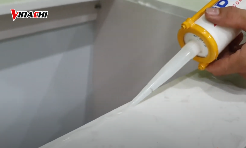Bơm keo silicon quanh mép lỗ khoét ở mặt bàn