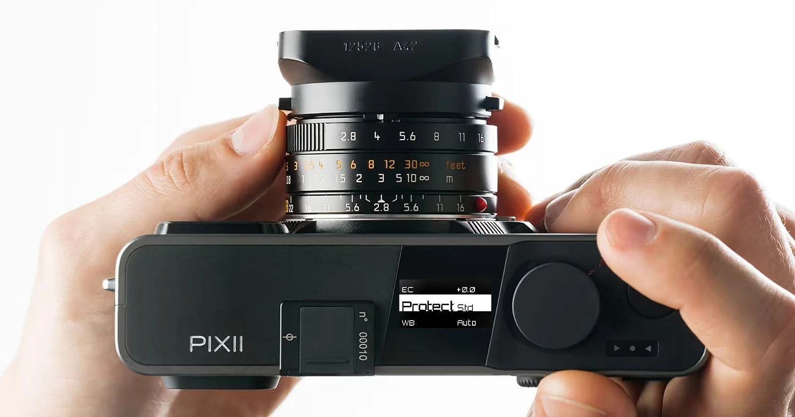 Nhiếp ảnh gia cầm trên tay thân máy ảnh Pixii màu đen với màn hình phụ nhỏ trên đỉnh máy