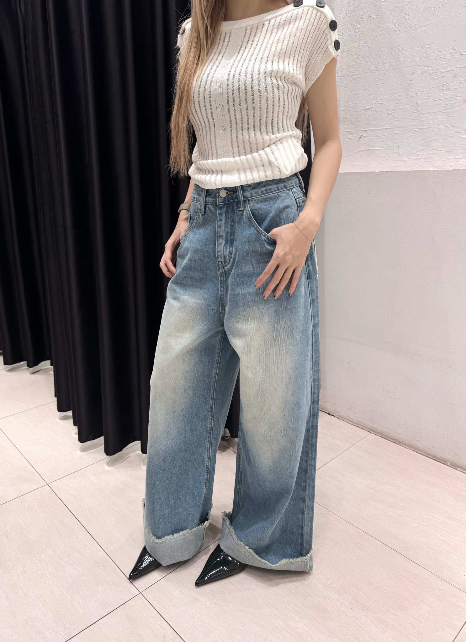 Quần jeans xanh gập gấu ống rộng.
