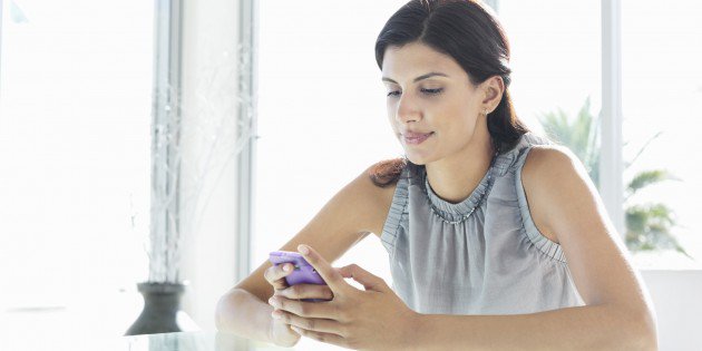 Businesswoman using cell phone at desk